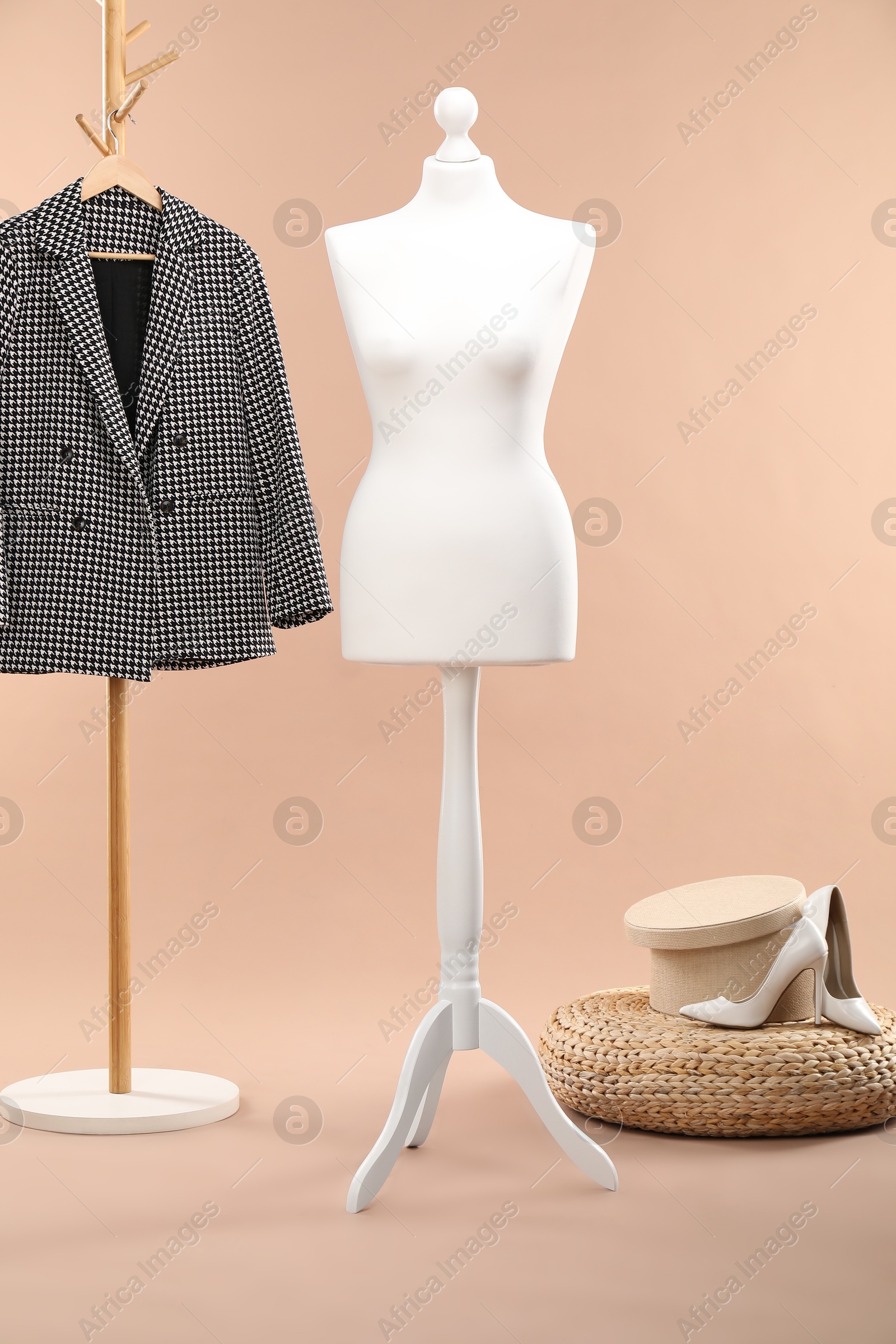 Photo of One female mannequin, pouf, shoes and rack with jacket against beige background