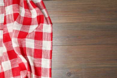 Photo of Crumpled tablecloth with checkered pattern on wooden table, top view. Space for text