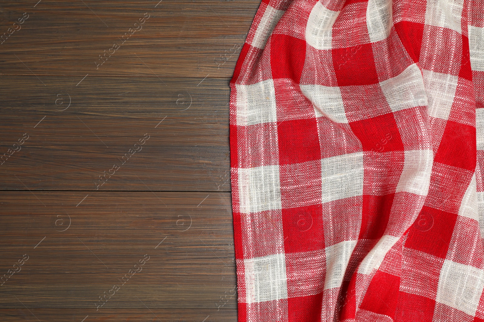 Photo of Crumpled tablecloth with checkered pattern on wooden table, top view. Space for text