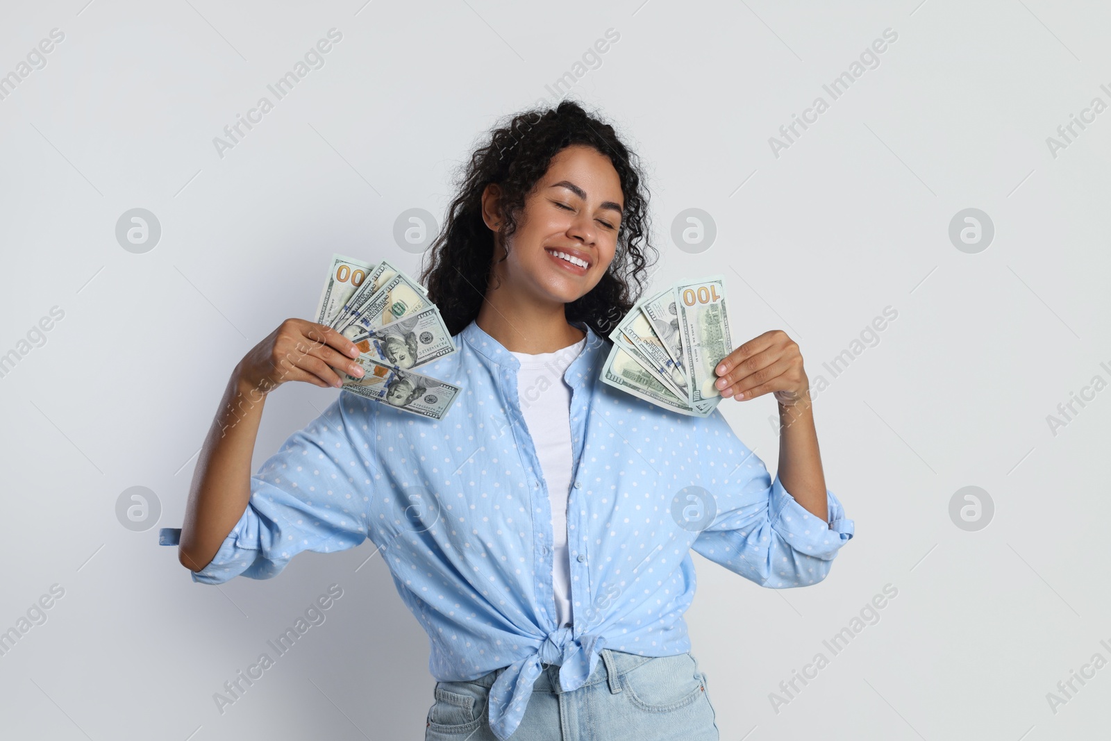 Photo of Happy woman with dollar banknotes on light grey background