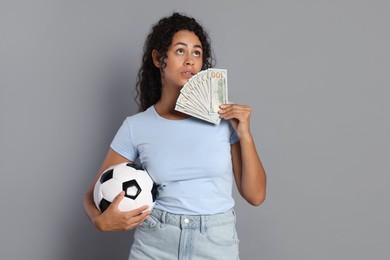 Photo of Woman with money and soccer ball on grey background