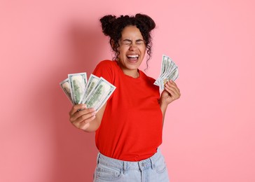 Happy woman with dollar banknotes on pink background