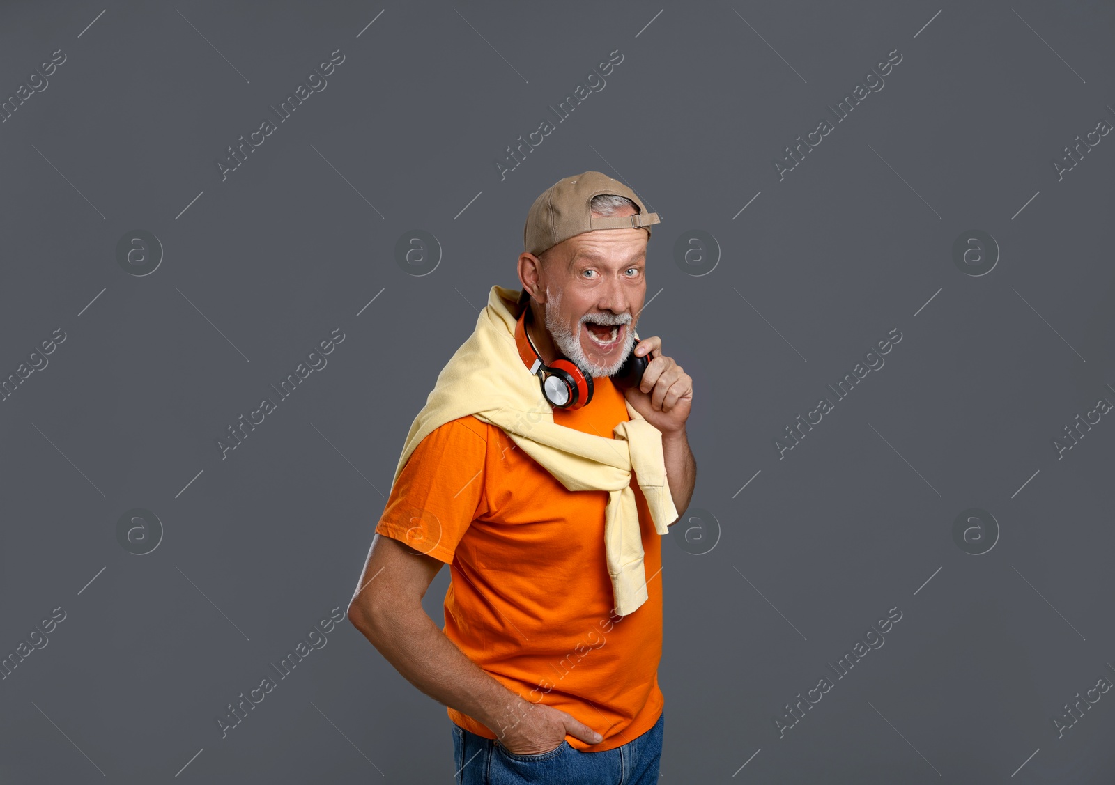 Photo of Portrait of emotional senior man with headphones on grey background