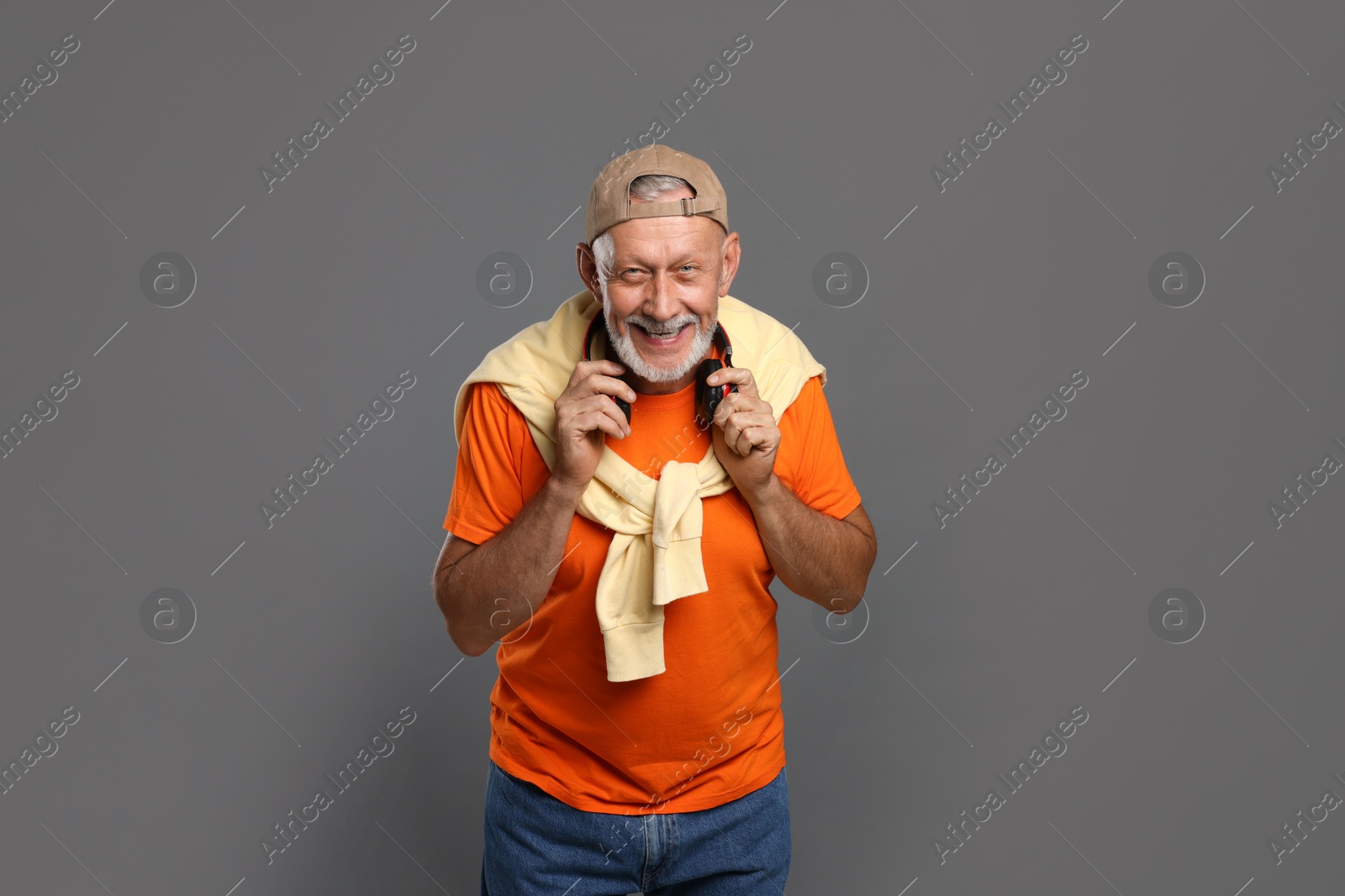 Photo of Portrait of happy senior man with headphones on grey background