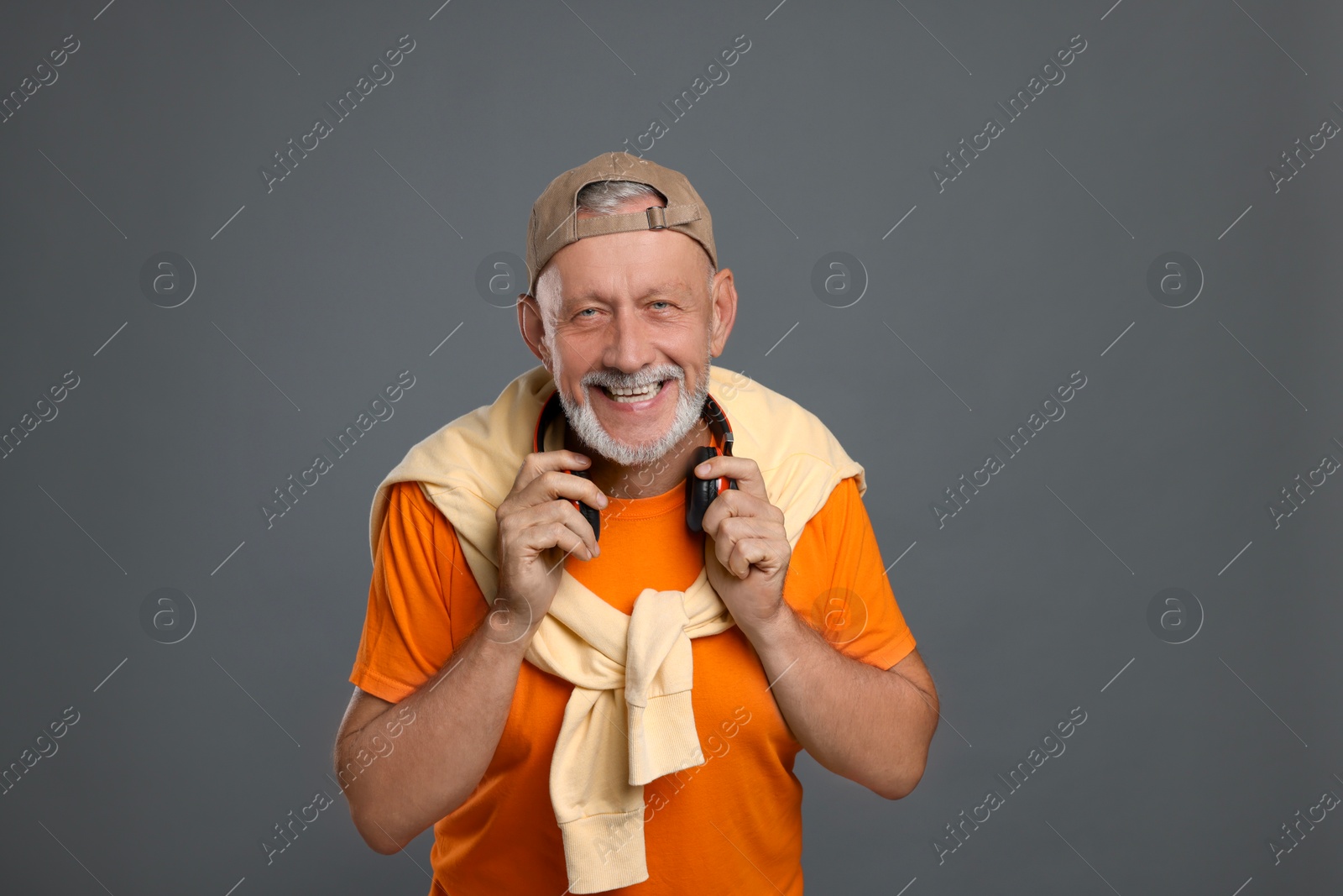 Photo of Portrait of happy senior man with headphones on grey background