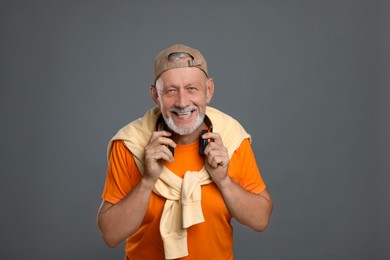 Photo of Portrait of happy senior man with headphones on grey background