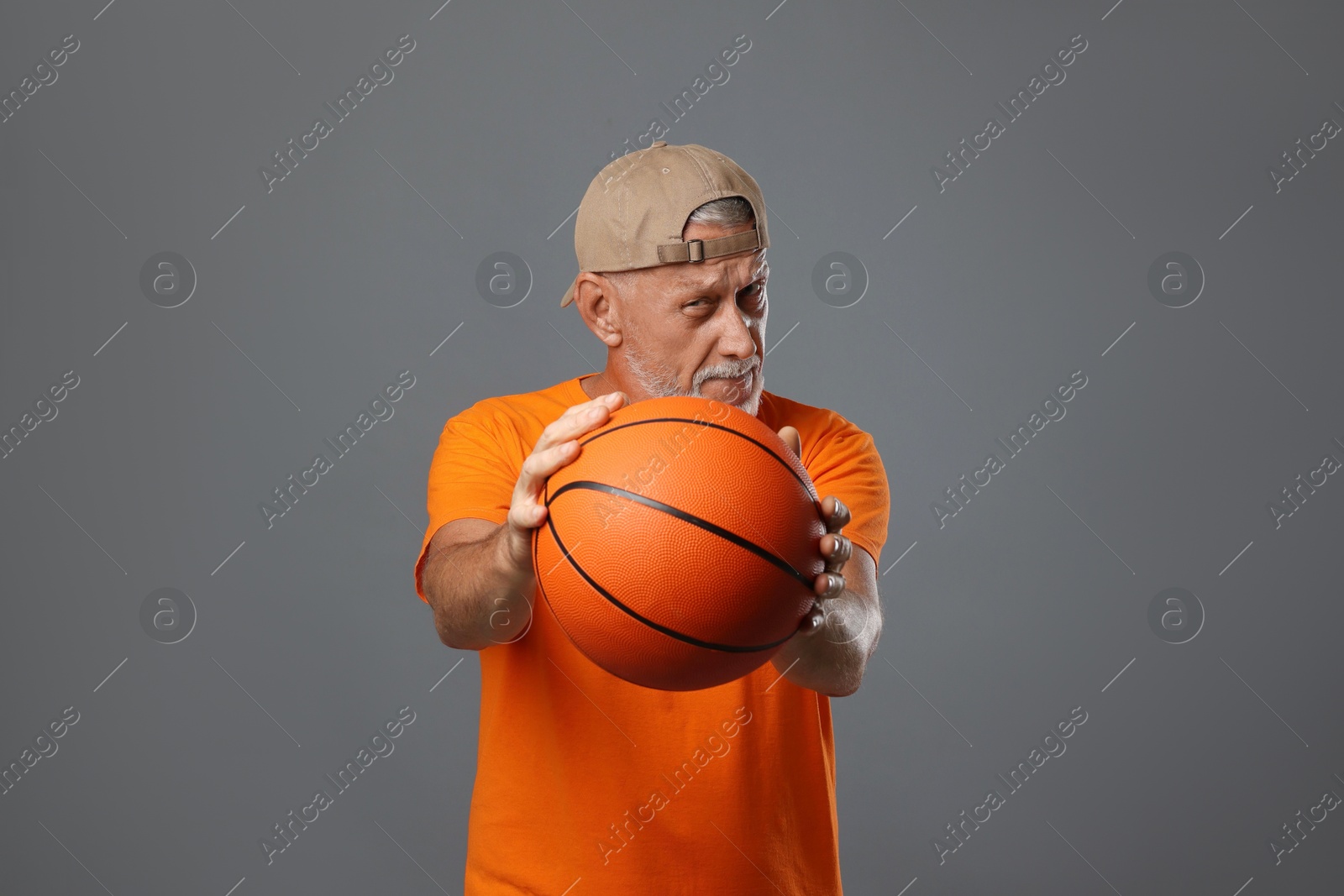 Photo of Portrait of handsome senior man with basketball ball on grey background