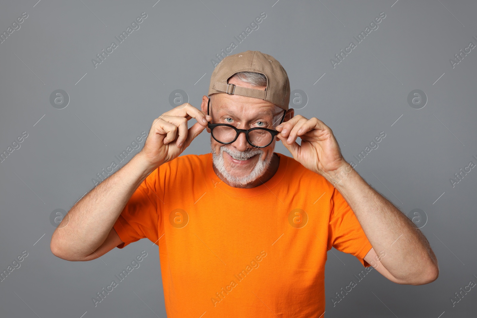 Photo of Portrait of funny senior man in glasses on grey background