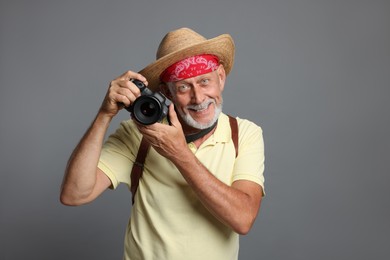 Portrait of happy senior man with camera on grey background