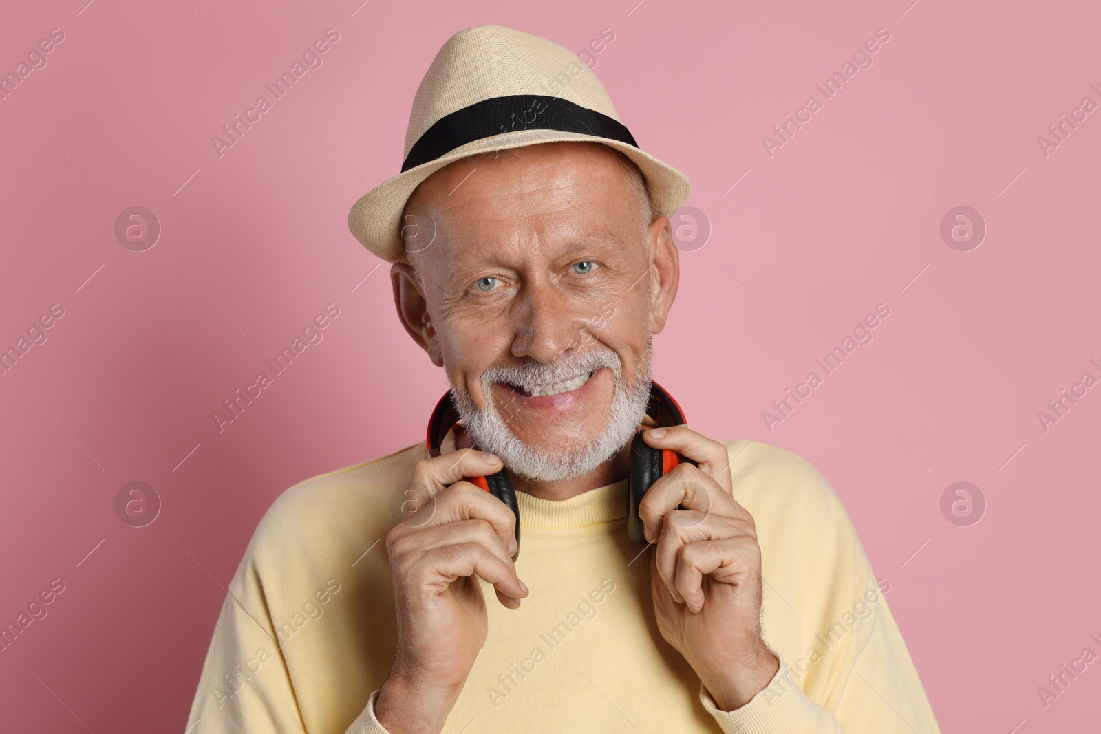 Photo of Portrait of happy senior man with headphones on pink background