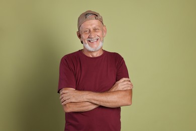 Portrait of happy senior man with crossed arms on green background