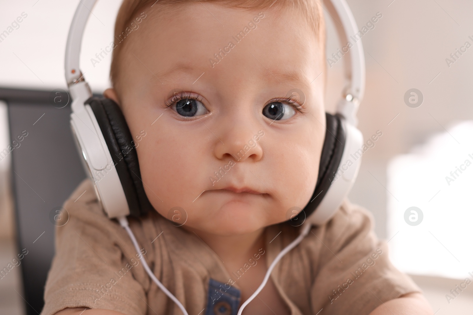 Photo of Cute little baby with headphones at home