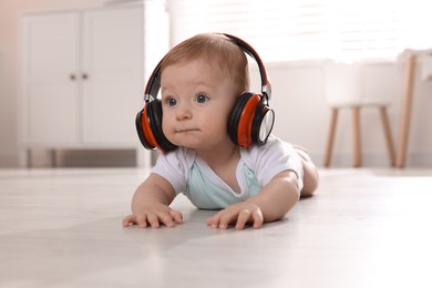 Cute little baby with headphones on floor at home