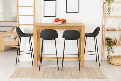 Photo of Bar stools near wooden table in room