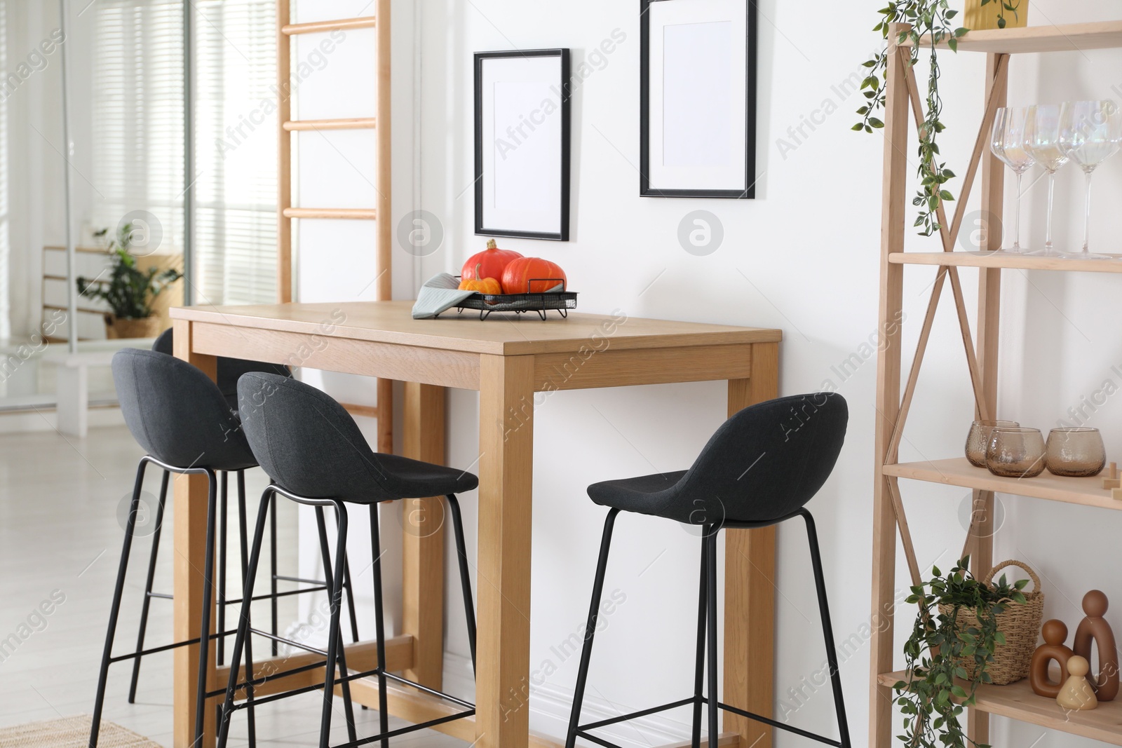 Photo of Bar stools near wooden table in room