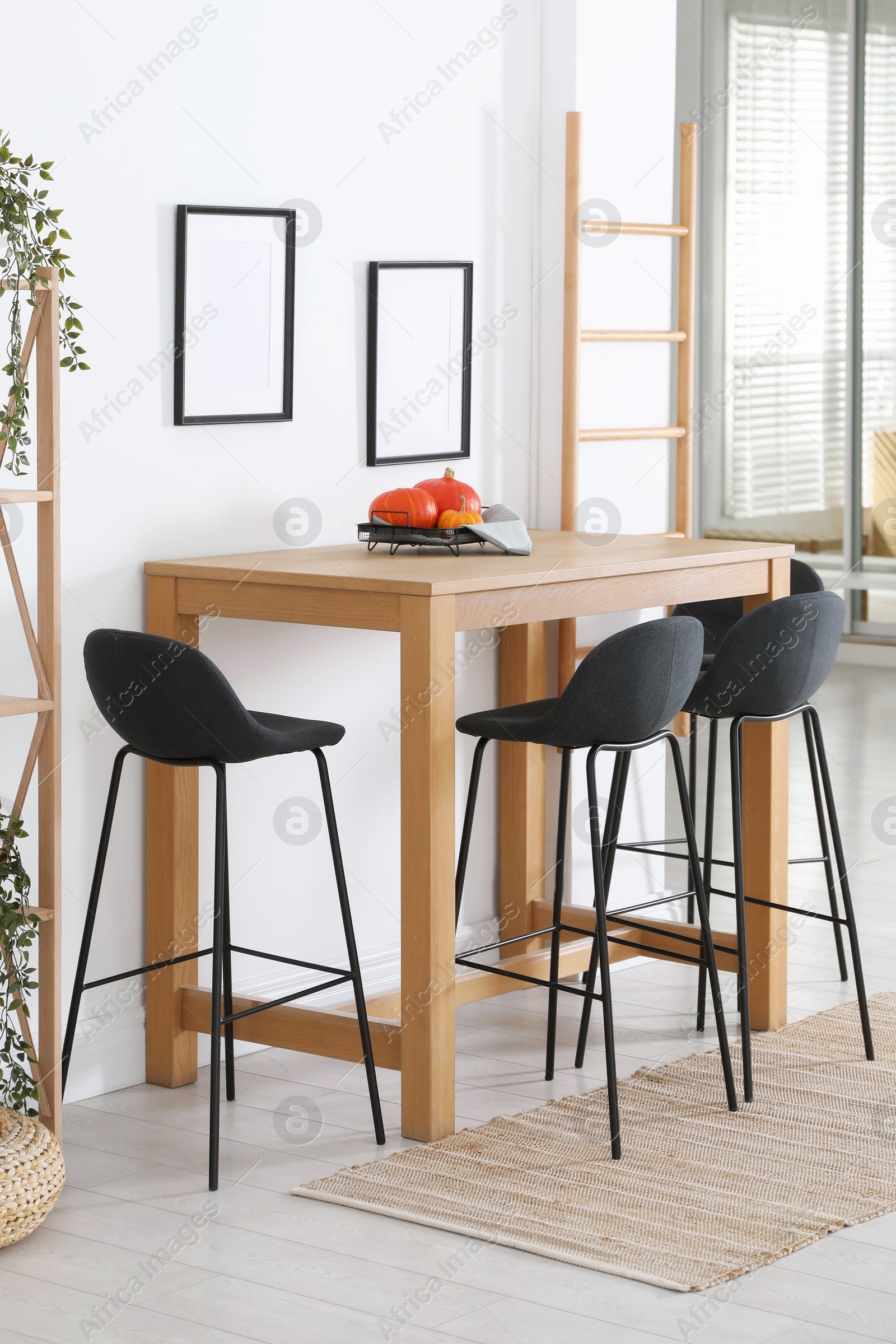 Photo of Bar stools near wooden table in room