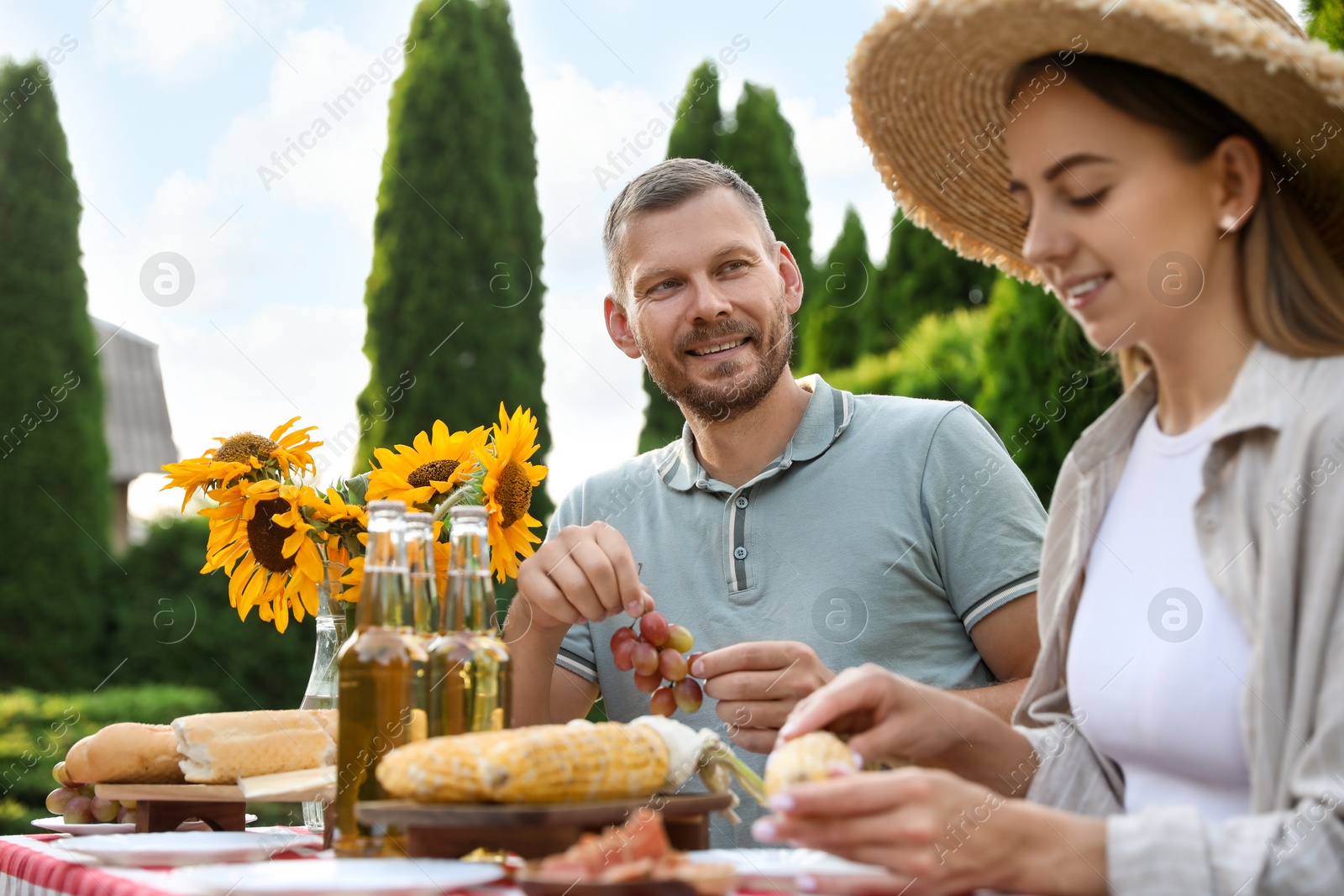 Photo of Couple having picnic at table in garden