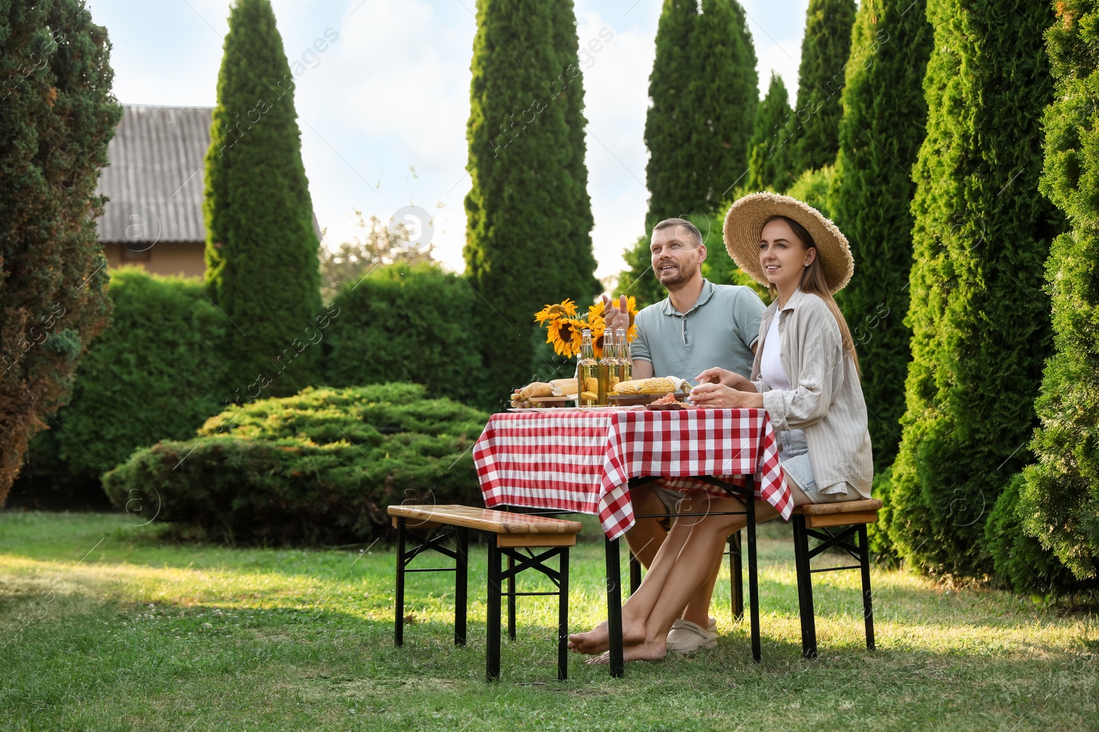 Photo of Couple having picnic at table in garden