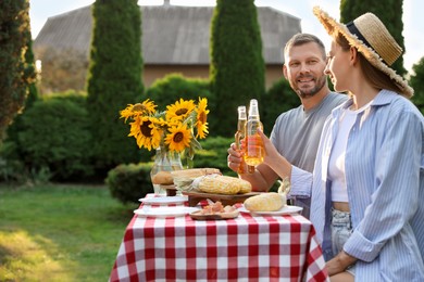 Friends with drinks enjoying picnic at table in garden