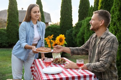 Photo of Couple enjoying picnic at table in garden