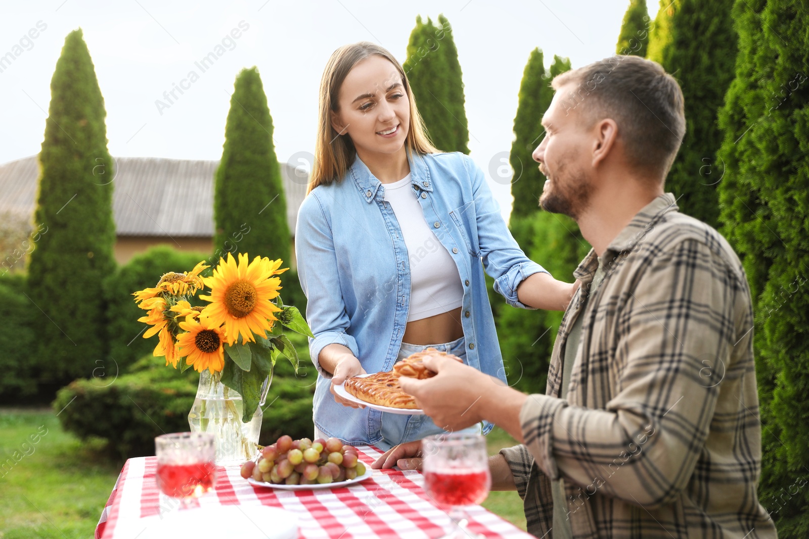 Photo of Couple enjoying picnic at table in garden