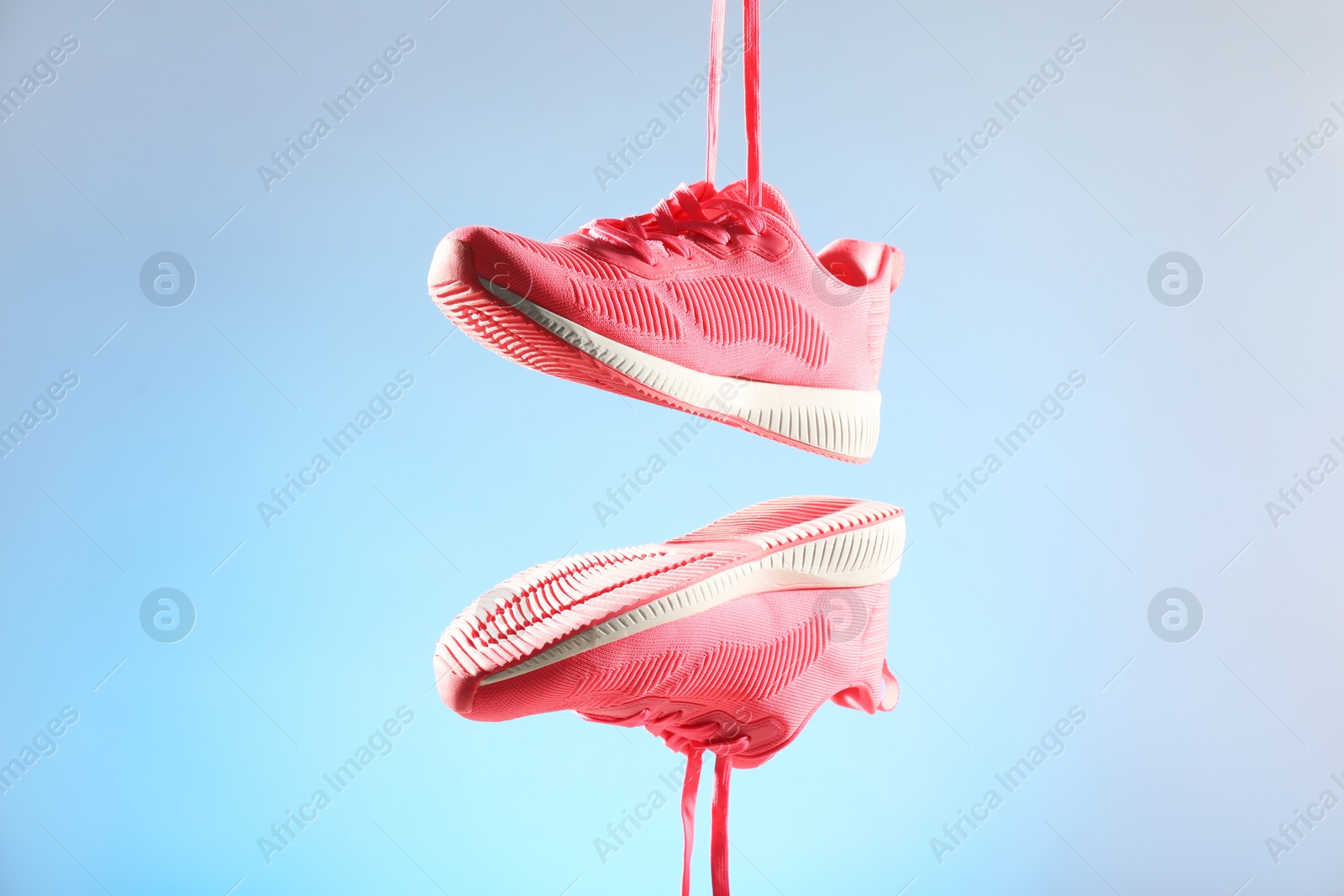 Photo of Pair of stylish sneakers in air against light blue background