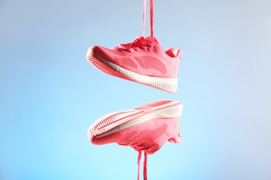 Photo of Pair of stylish sneakers in air against light blue background