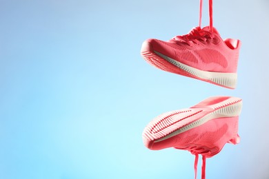 Photo of Pair of stylish sneakers in air against light blue background, space for text