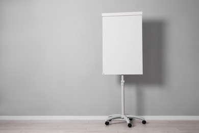 Flip chart near grey wall indoors. Mockup for design