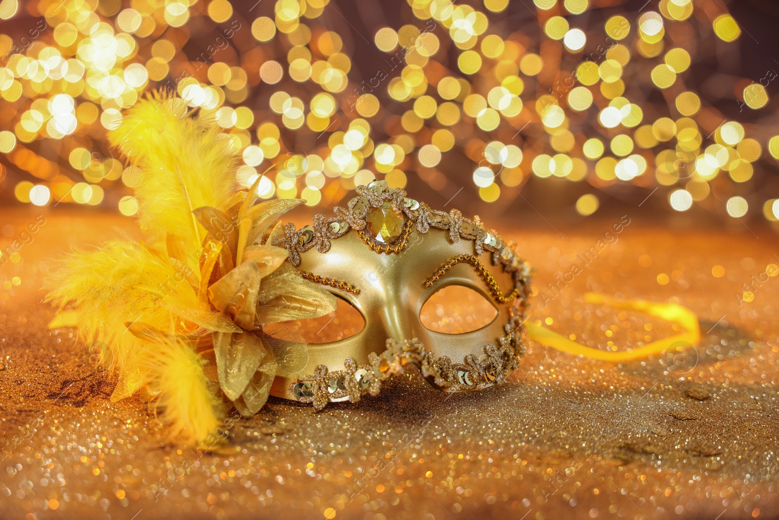 Photo of Beautiful carnival mask on golden shiny background, bokeh effect