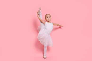 Little girl pretending to be ballerina on pink background. Dreaming of future profession