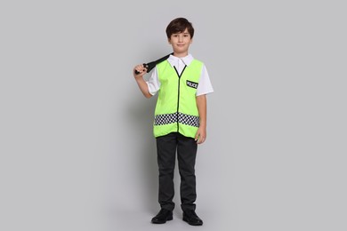 Boy pretending to be policeman on light grey background. Dreaming of future profession