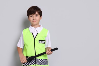 Photo of Boy pretending to be policeman on light grey background, space for text. Dreaming of future profession