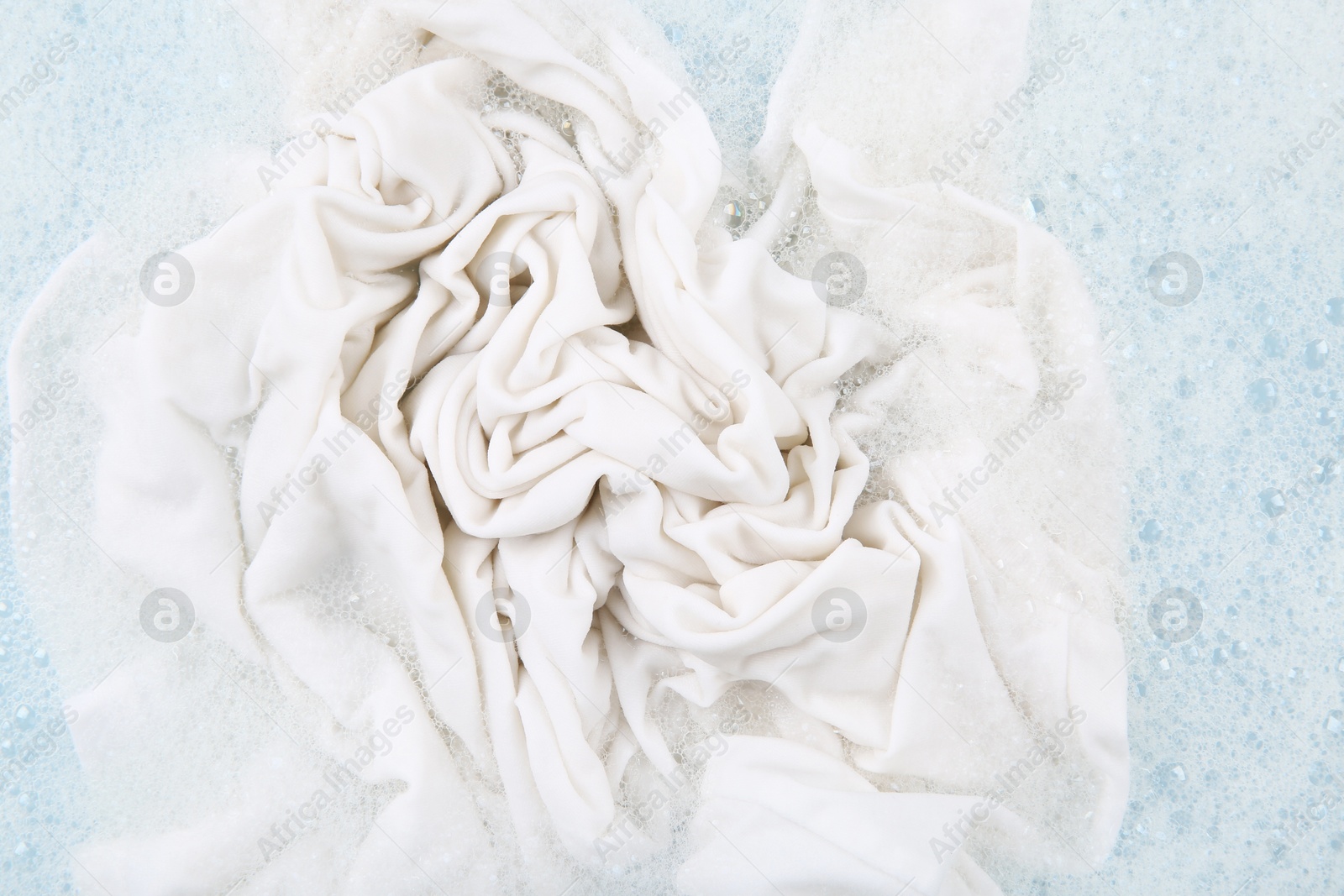 Photo of Washing laundry in water with foam, top view