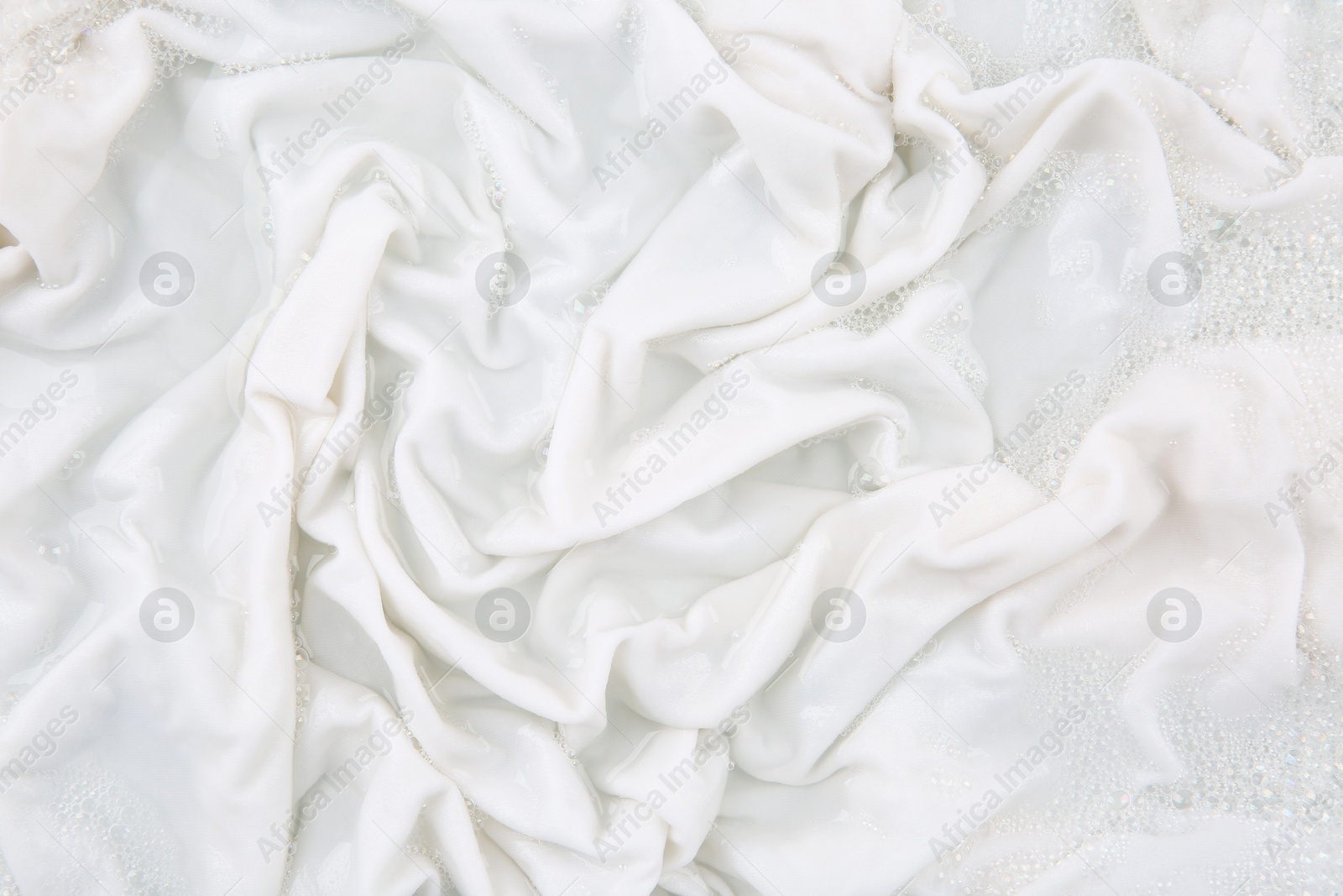 Photo of Washing laundry in water with foam, top view