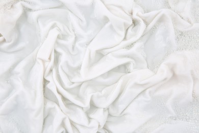 Photo of Washing laundry in water with foam, top view