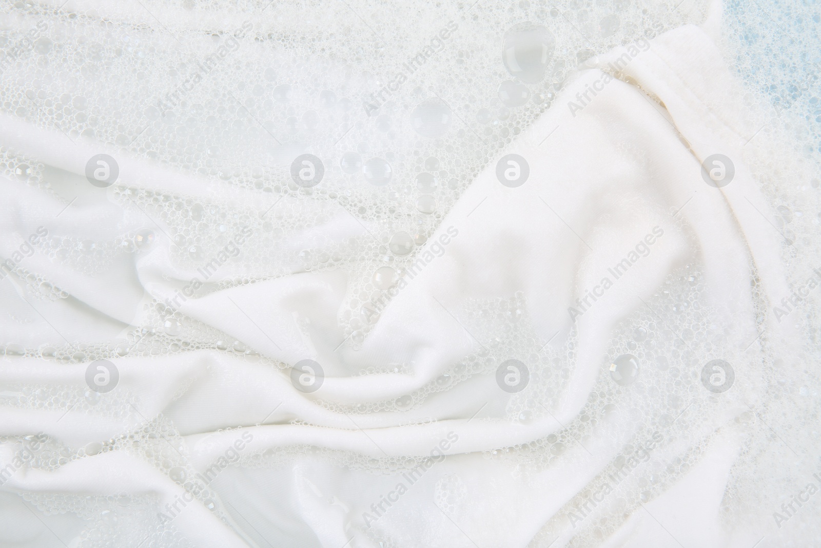 Photo of Washing laundry in water with foam, top view