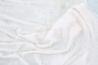 Photo of Washing laundry in water with foam, top view