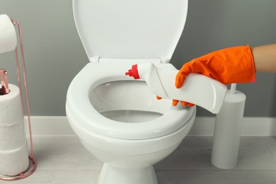 Photo of Woman cleaning toilet with detergent in bathroom, closeup