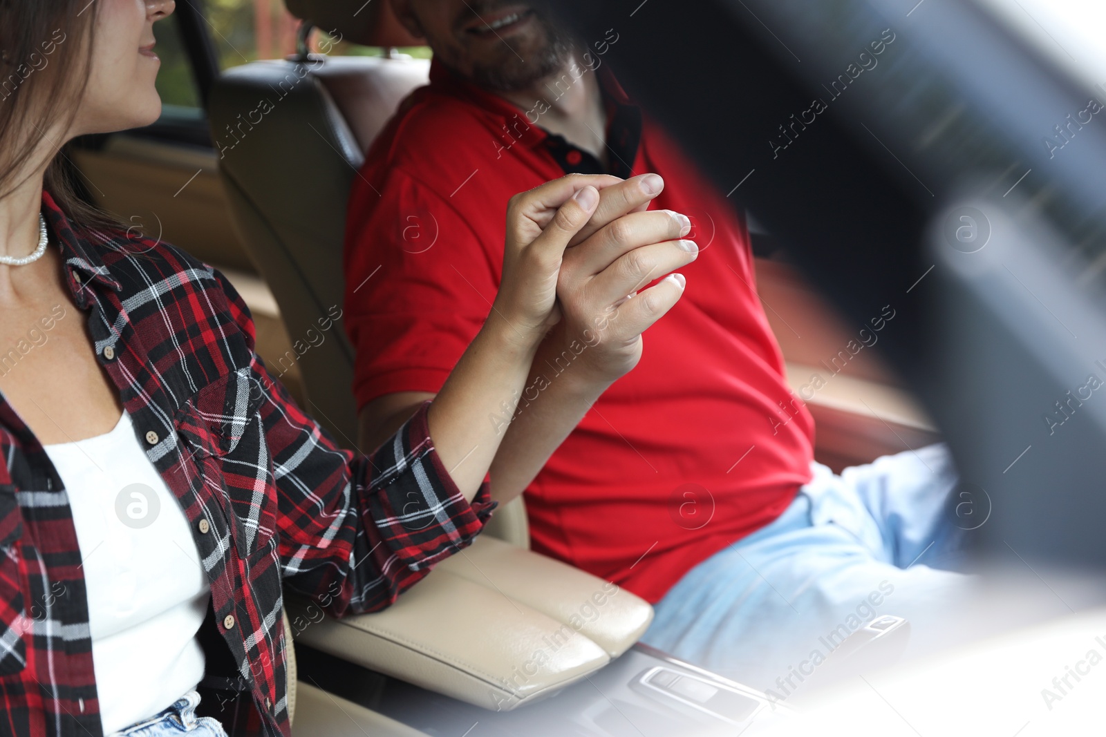 Photo of Lovely couple holding hands together while traveling by car, closeup