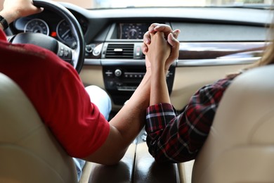 Photo of Lovely couple holding hands together while traveling by car, closeup