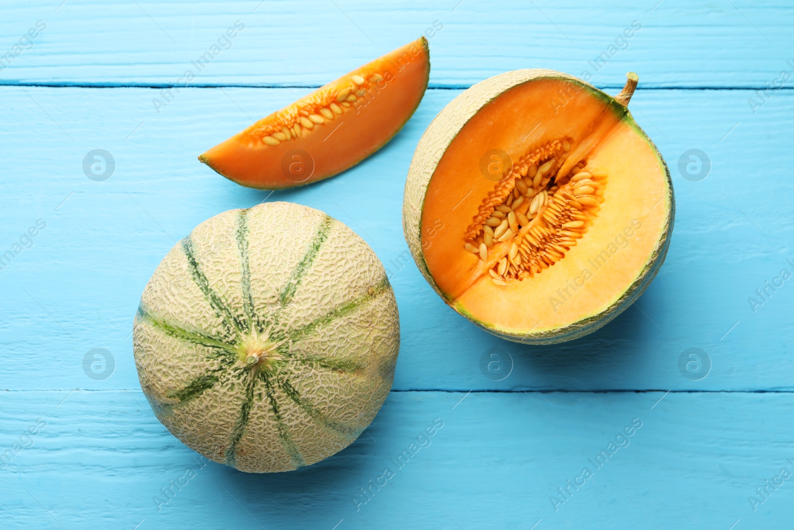 Photo of Cut and whole ripe Cantaloupe melons on light blue wooden table, flat lay