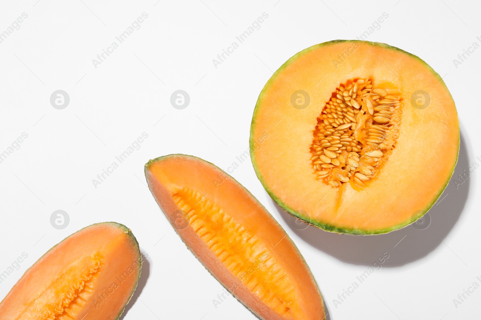 Photo of Pieces of fresh Cantaloupe melon on white table, flat lay. Space for text