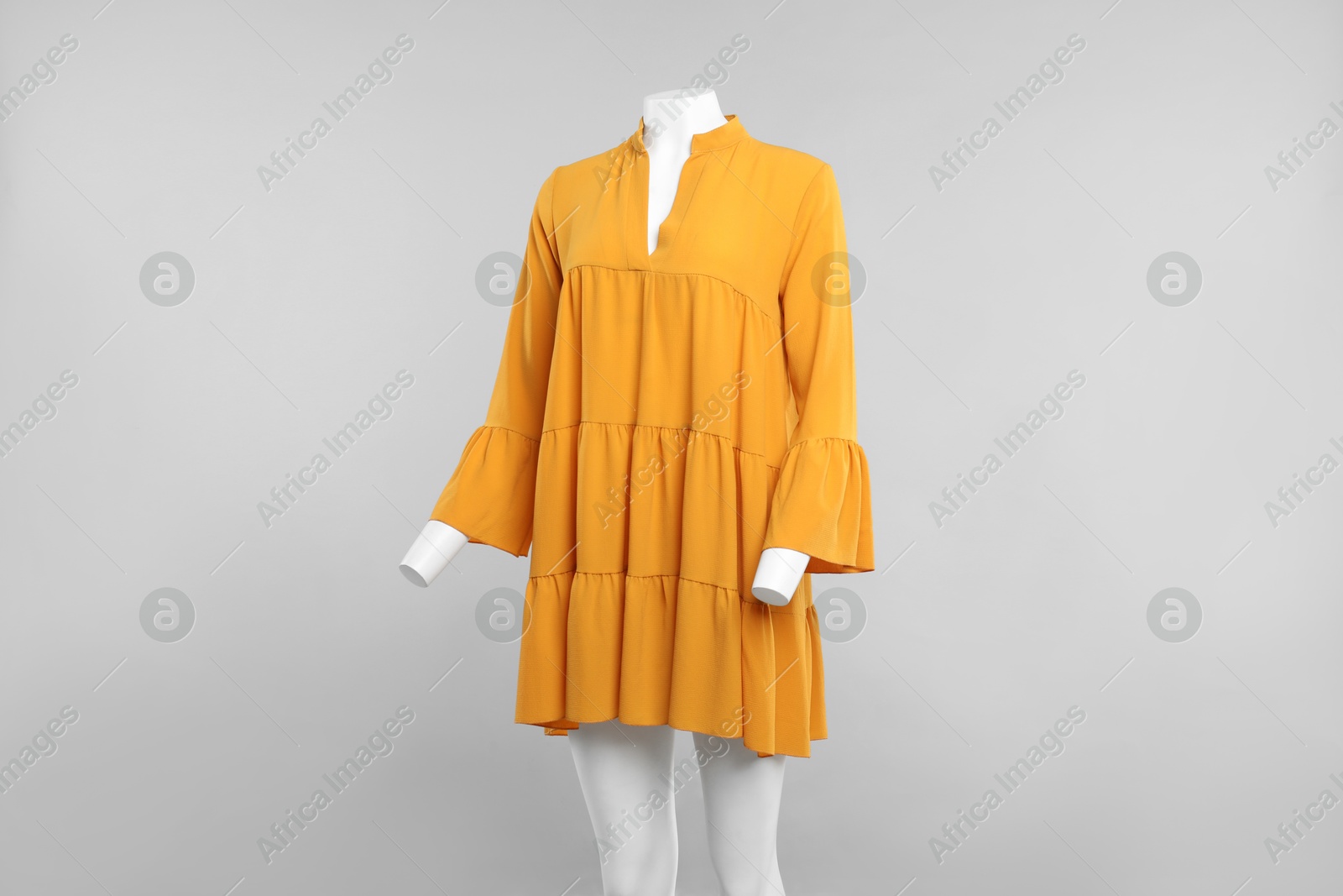 Photo of Female mannequin with stylish orange dress on light background