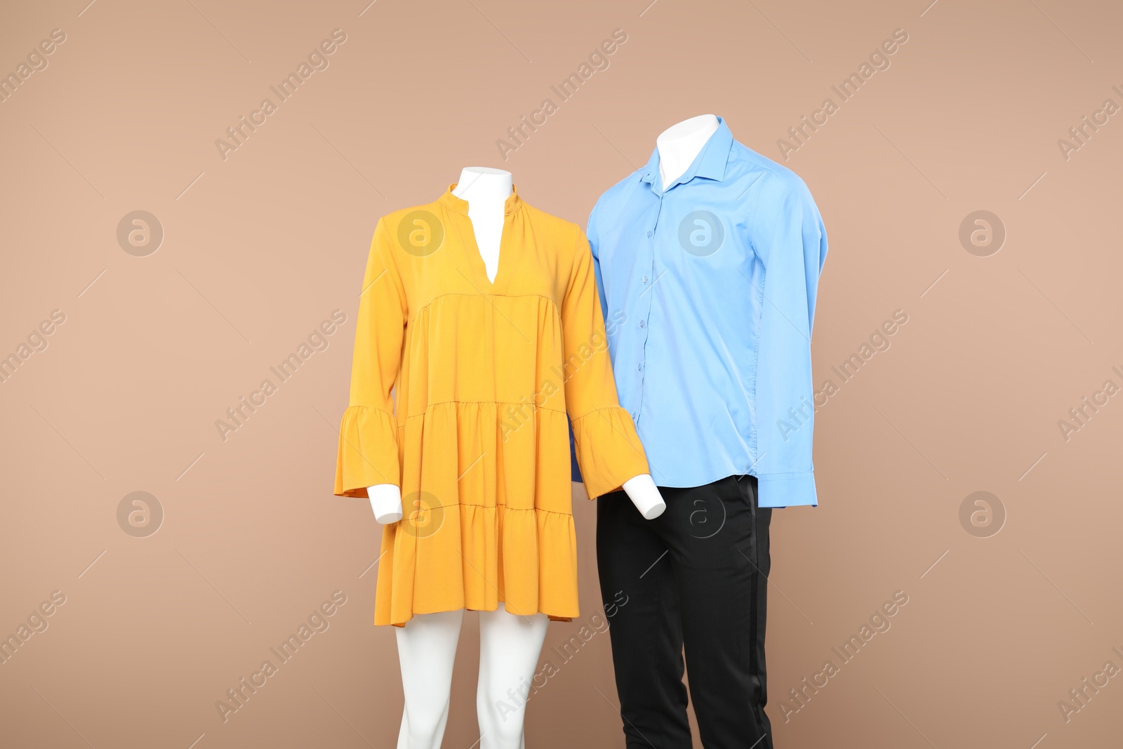 Photo of Female and male mannequins with stylish outfits on beige background