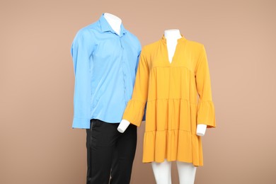 Photo of Female and male mannequins with stylish outfits on beige background