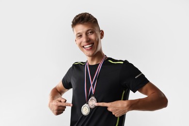 Happy winner pointing at his medals on light grey background