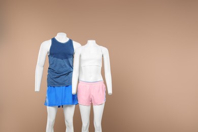 Photo of Female and male mannequins with stylish sportswear on beige background, space for text