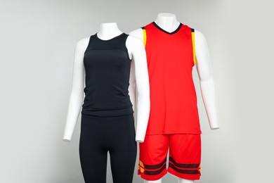 Photo of Female and male mannequins with stylish sports outfits on light grey background