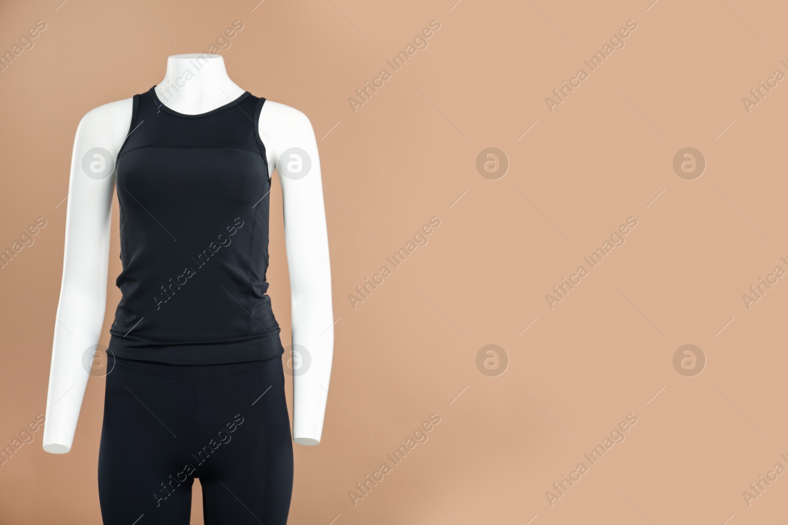 Photo of Female mannequin with stylish sports outfit on light brown background, space for text